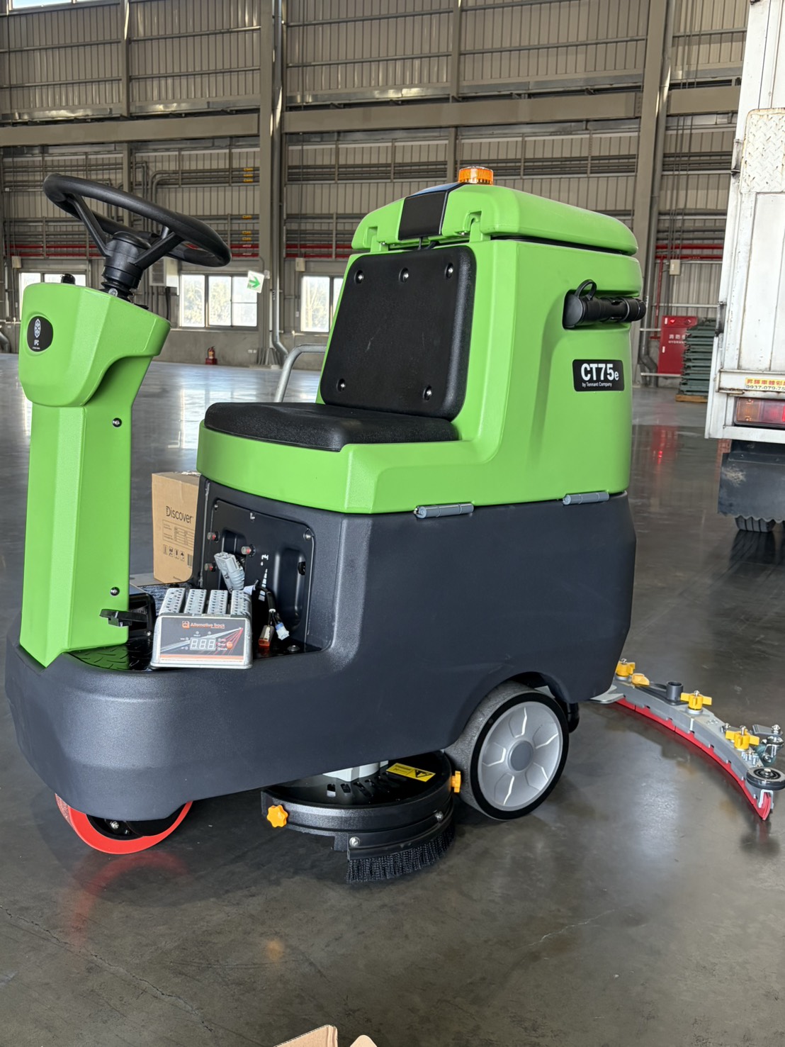 An ALT-700 charger integrated inside the battery compartment of an IPC CT75e ride-on floor scrubber at the Joynice service facility in Taiwan.