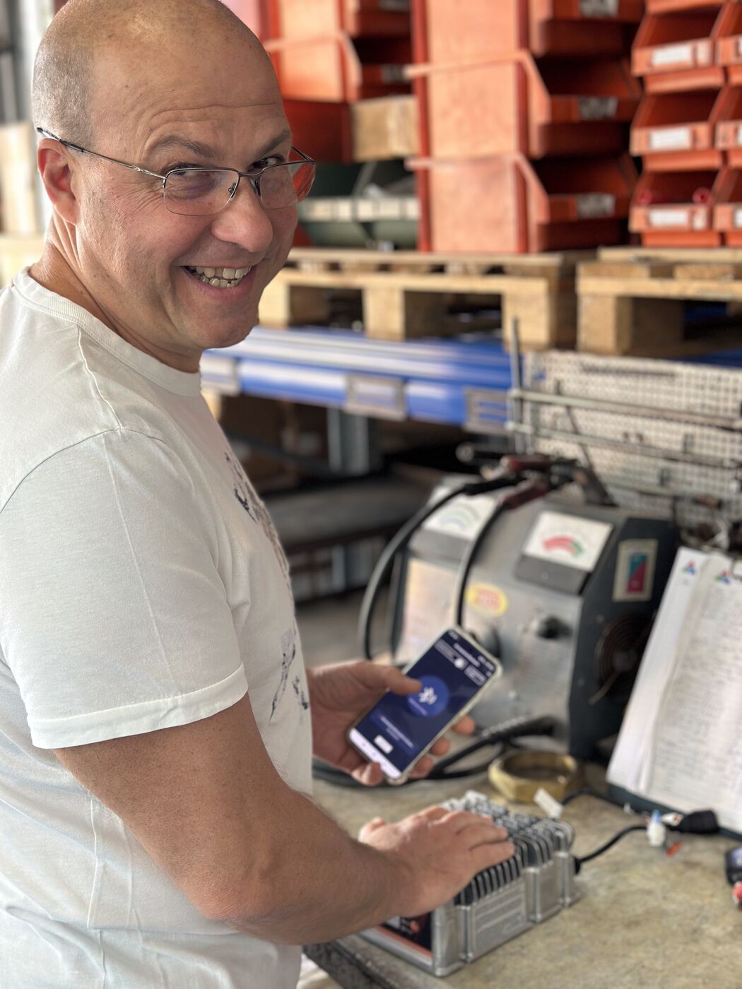Workshop technician with an ALT charger in hand